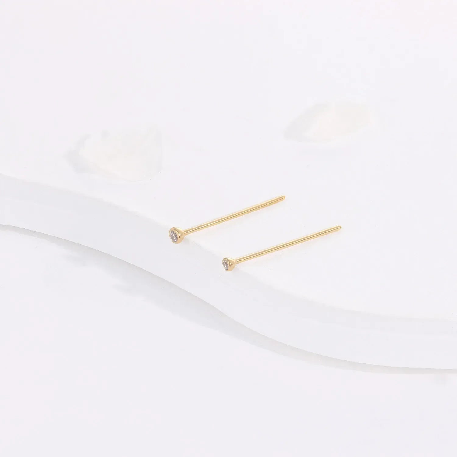 Minimalist gold stud earrings with small clear stones on white background, Rosary Milano jewelry