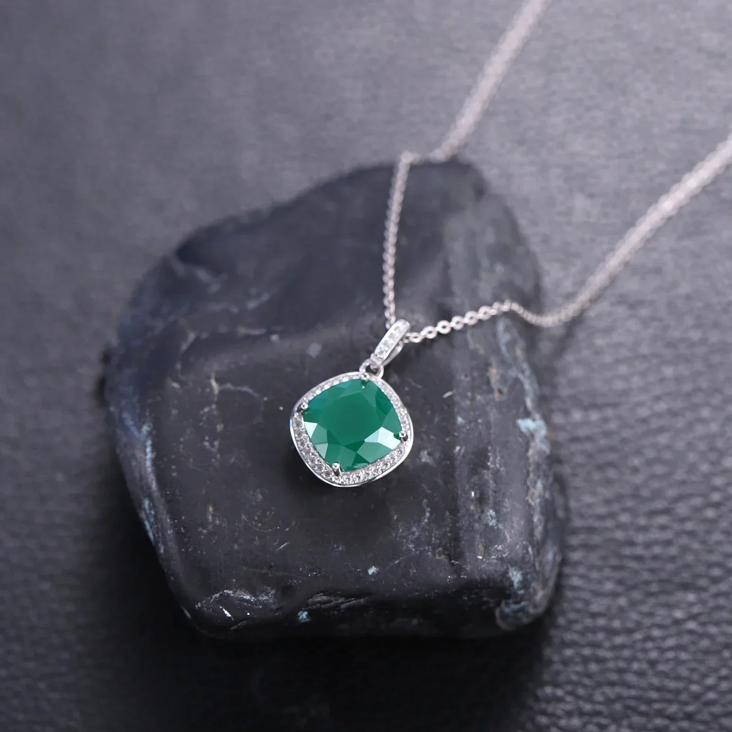 Emerald pendant necklace with silver chain displayed on black stone, Rosary Milano jewelry