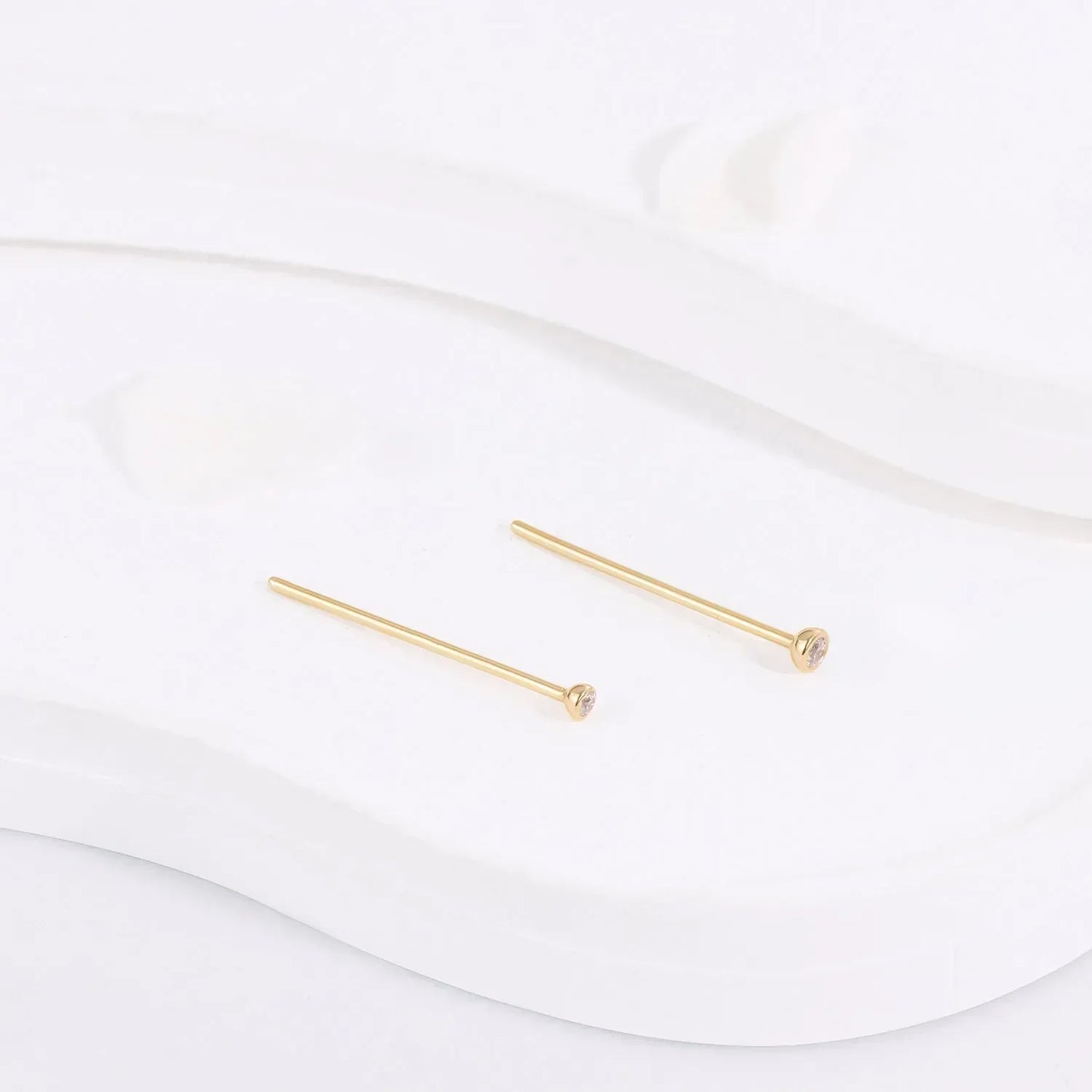 Minimalist gold stud earrings with small gemstones on white display, Rosary Milano jewelry