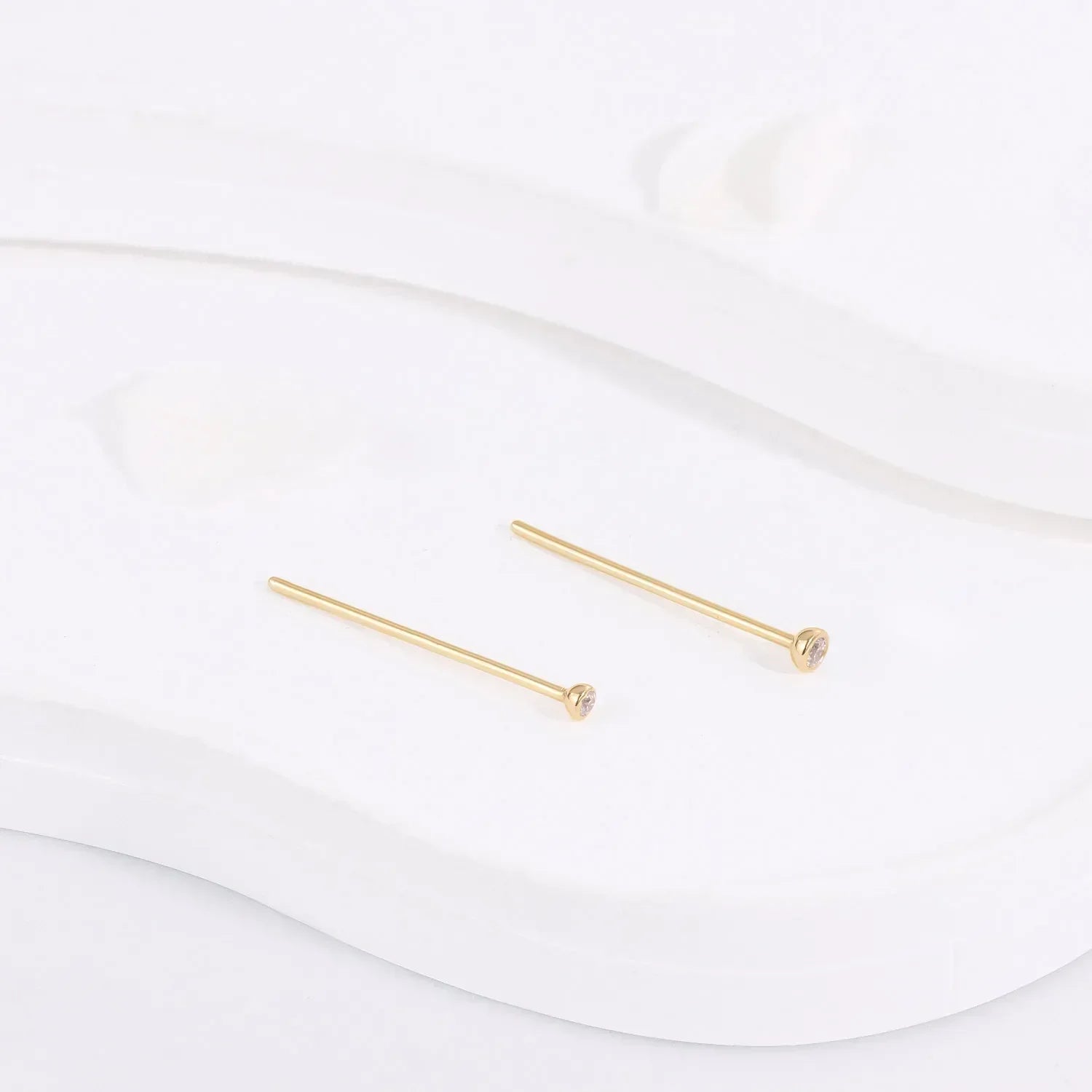 Minimalist gold stud earrings with small gemstones on white display, Rosary Milano jewelry
