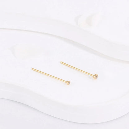 Minimalist gold stud earrings with small gemstones on white display, Rosary Milano jewelry