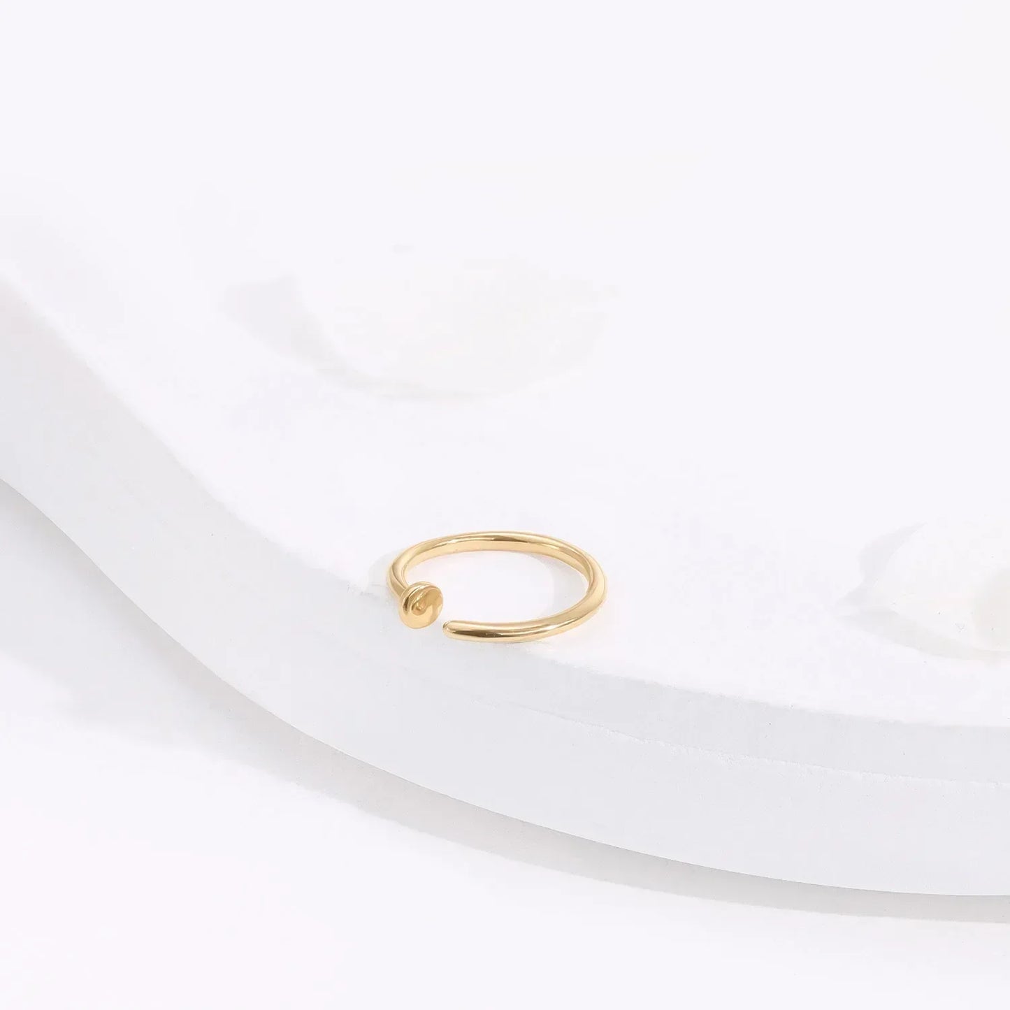 Minimalist gold open ring on white surface, Rosary Milano fashion jewelry
