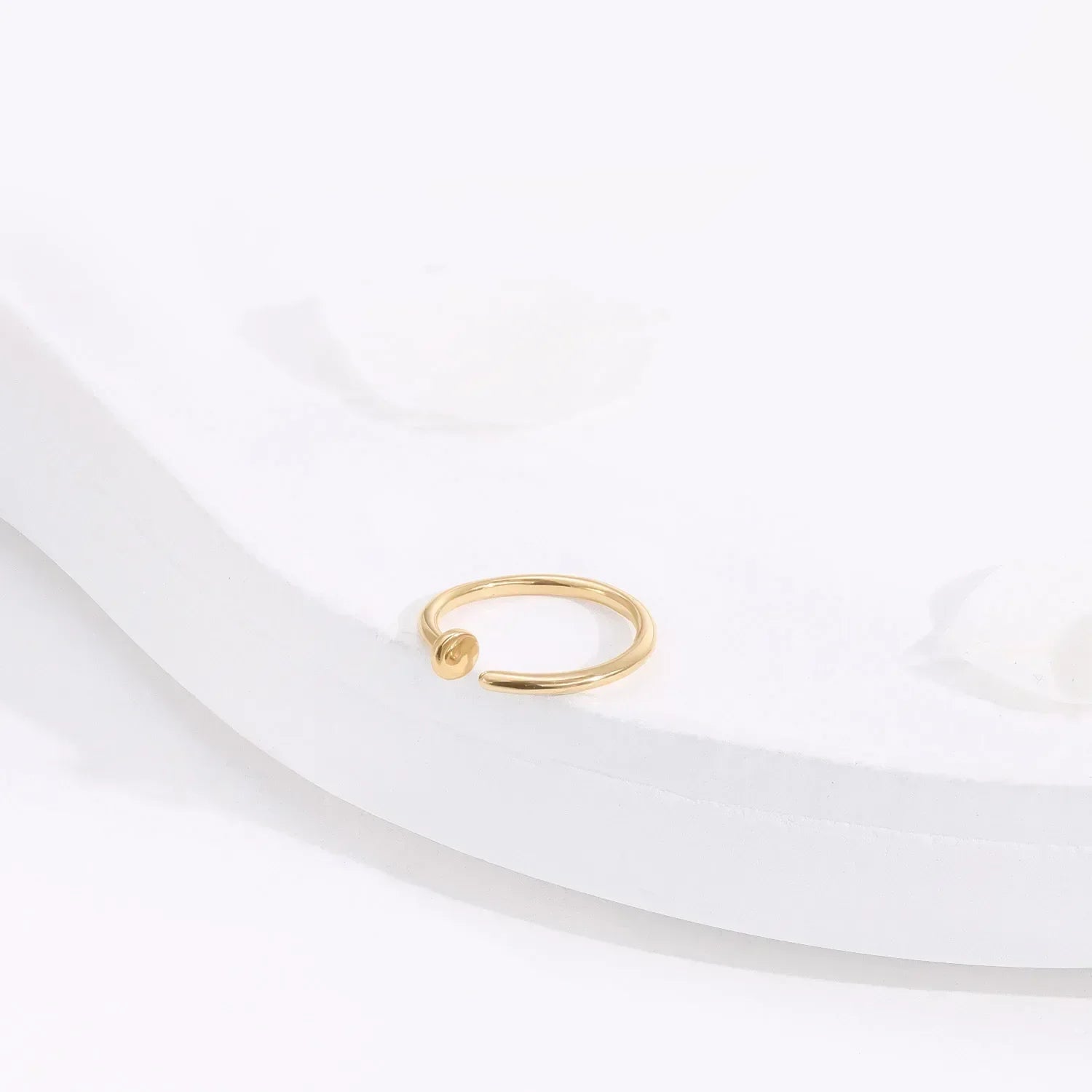 Minimalist gold open ring on white surface, Rosary Milano fashion jewelry