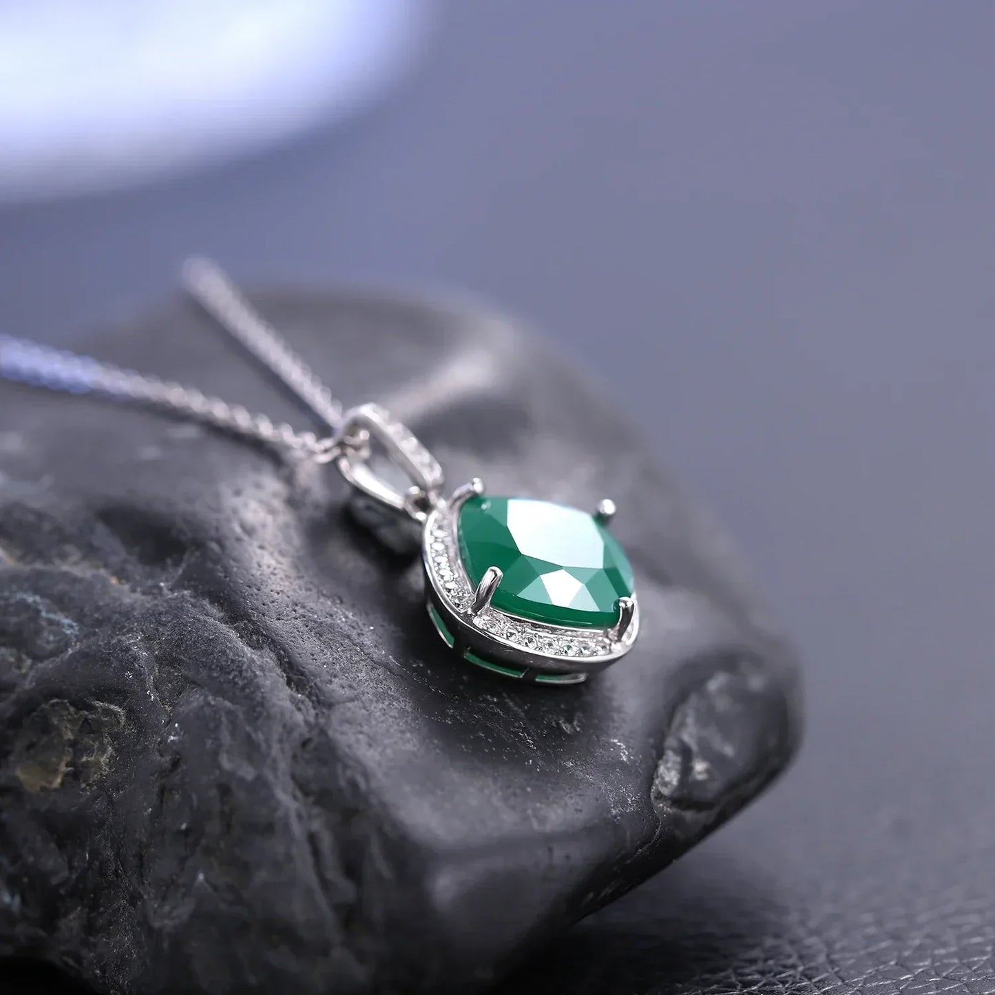 Emerald green gemstone necklace with silver chain from RosaryMilano on dark stone background
